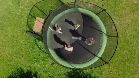 Aerial Shooting of a Little Girls Company Jumping and Running on the Trampoline