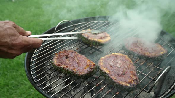 Steak covered with minced meat and cheddar cheese is being cooked on a grill.