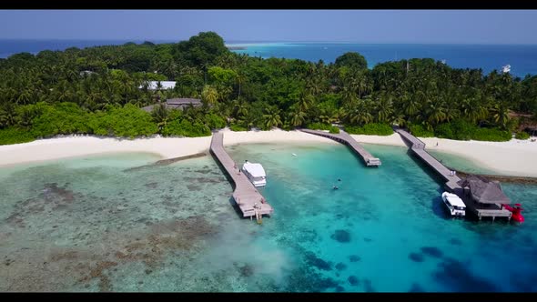 Aerial panorama of tranquil tourist beach holiday by blue lagoon with clean sandy background of jour