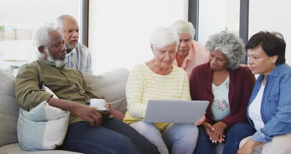 Happy senior diverse people talking and using laptop at retirement home