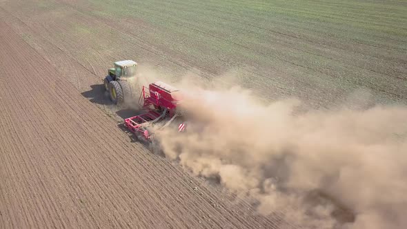 Top Down Aerial View of Green Tractor Cultivating Ground and Seeding a Dry Field