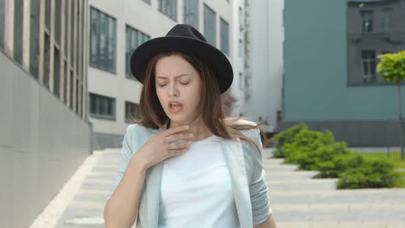 A Woman Walking Down the Street and Coughing. A Woman with Signs of Illness Coughs and Covers Her