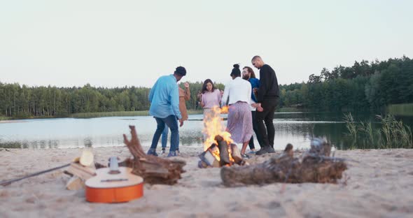 Friends are Dancing Party on the Beach By the Lake Until Morning Early Dawn Campfire is Burning