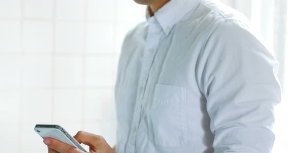 Man using mobile phone while having cup of coffee in kitchen 4k