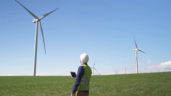 Collar Worker Standing Near Wind Mill and Using His Tablet