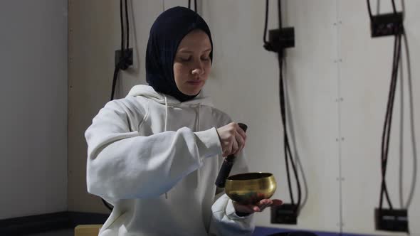 A Young Woman in Hijab Does Ritual with Driving the Pusher Along the Edges of the Tank