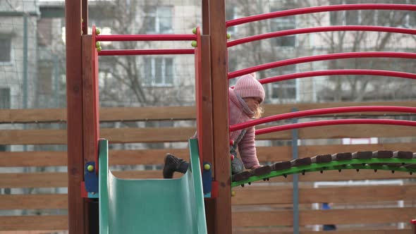 Toddler Girl Slides Down the Children's Slide at Local Playground