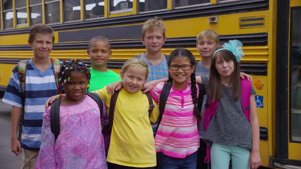 Portrait of group of students in front of school bus