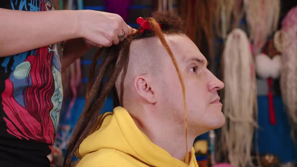 Unrecognizable Person Makes Hairstyle for Young Man in Salon