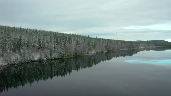 A glassy calm ice cold lake and forest in Dalarna, Sweden AERIAL SHOT