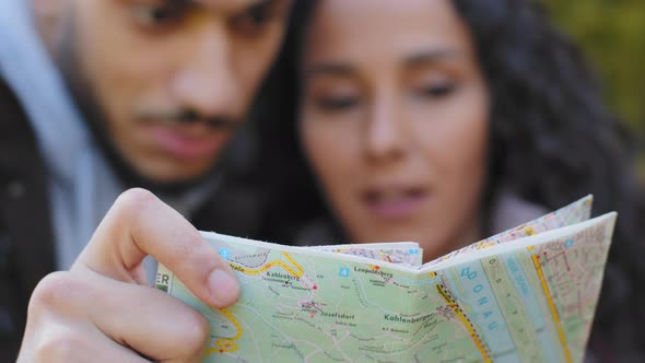 Out of Focus Young Hispanic Couple Backpackers Looking at Paper Map Looking for Right Route Man and