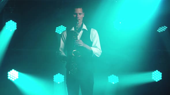 A Young Retro Stylish Guy Plays on the Golden Shiny Saxophone in the Turquoise Spotlights on Stage