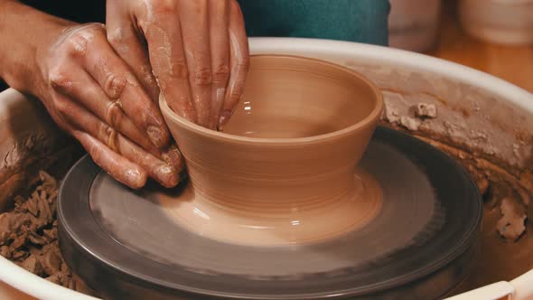 Man's Hands Sculpting a Pot Out From the Clay in Workshop