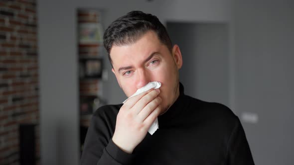 The young man is not healthy and does not feel well. He coughs. He blows his nose into a napkin