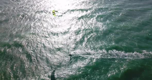 Aerial drone view of a man kiteboarding on a kite board.