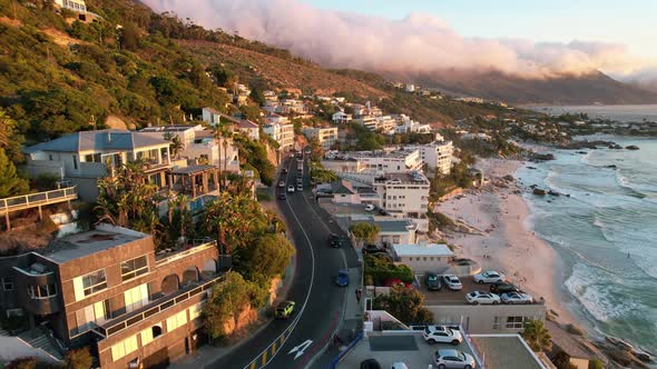 cars drive on road above Clifton Beach in Cape Town, South Africa at sunset, aerial