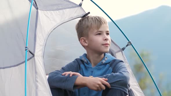 Hiker Child Boy Sitting Inside a Tent in Mountain Campsite Enjoying View of Nature