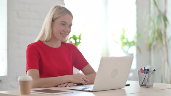 Young Blonde Woman Talking on Video Call on Laptop in Office