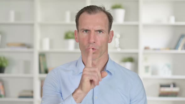 Portrait of Middle Aged Businessman Putting Finger on Lips