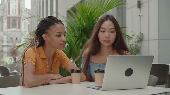 Two Beautiful Girls with Laptop Sitting in Cafe of Urban City Background