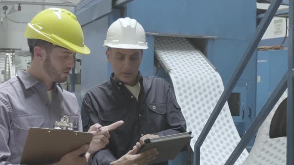 Factory workers with digital tablet and clipboard in factory