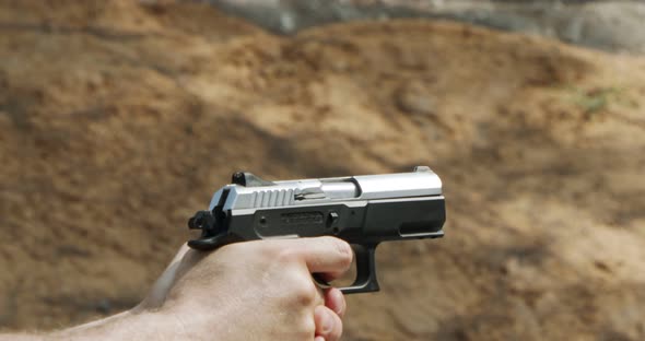 Slow motion of a hand gun firing in a firing range with cartridge flying away