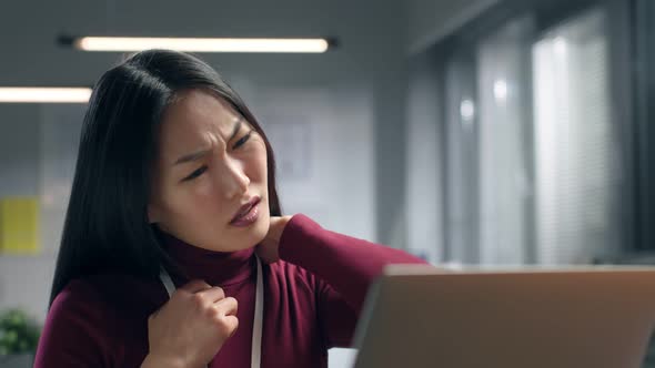 Asian Businesswoman Suffering From Pain in Neck Working at Desktop