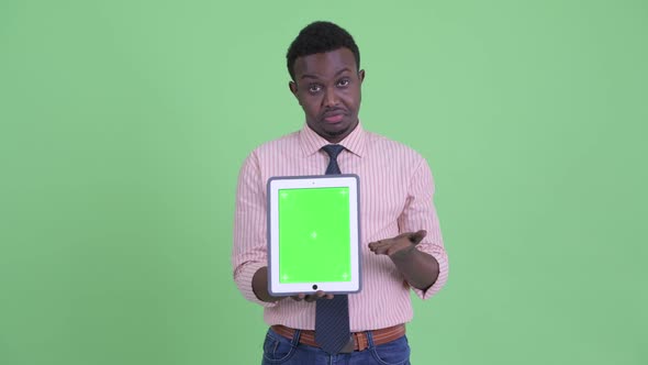 Stressed Young African Businessman Showing Digital Tablet