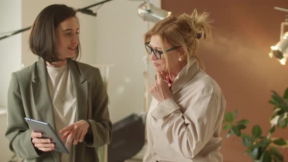 Mixed Age Female Colleagues Using Tablet and Chatting at Work