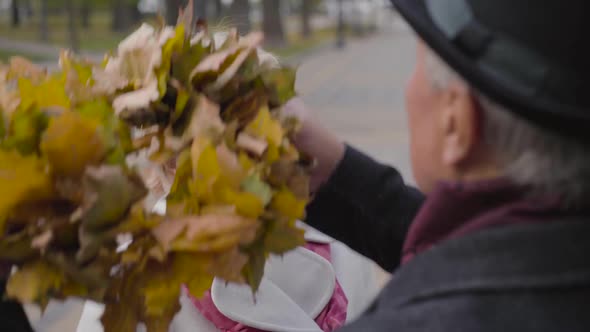 Senior Caucasian Man Putting Wreath Made of Yellow Leaves on the Head of His Adorable Wife