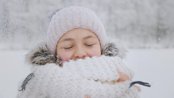 Many Snowflakes Fall on the Face of a Smiling Girl in Winter Time