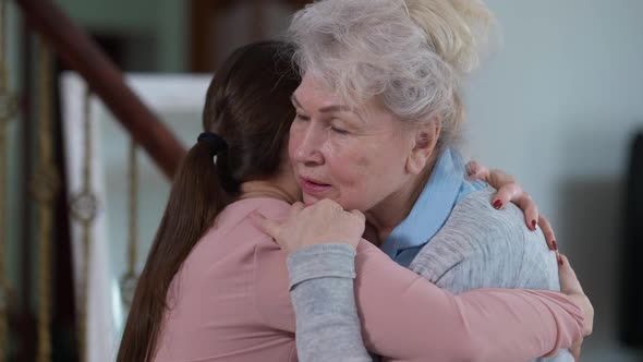 Portrait of Glad Caucasian Senior Grandmother Hugging Millennial Granddaughter Talking Caressing