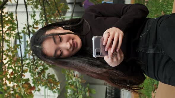 Korean Girl Sitting On The Street With Mobile Phone In Her Hands