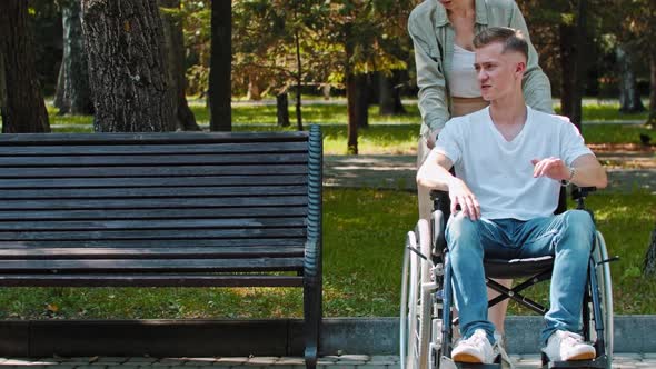 A Couple Walking in Park a Guy in a Wheelchair Talking with His Girlfriend and He Sits Next to Him