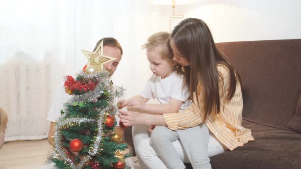 Children and Parents Decorating Christmas Tree at Home