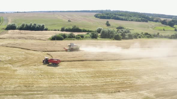 Aerial Drone Shot  a Combine Harvester and a Tractor in a Field in a Rural Area on a Sunny Day