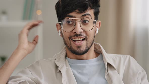 Closeup Arabic Young Bearded Guy with Glasses Speaks Online Call Using Wireless Modern Headphones