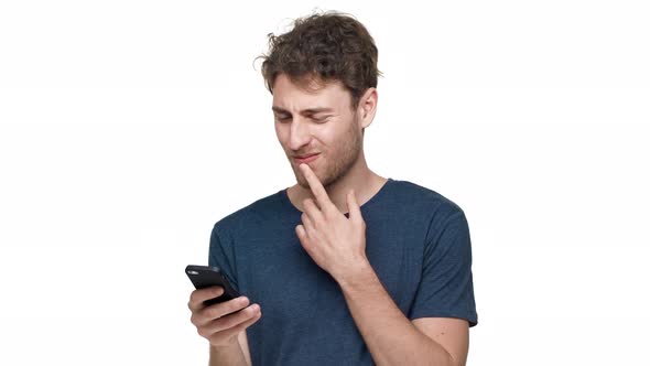 Portrait of Young Pleased Man Having Bristle Using Smartphone and Scrolling News Feed Isolated Over
