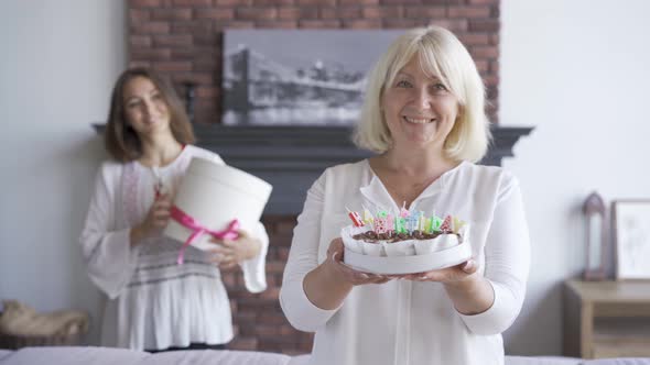 Happy Senior Woman Showing a Cake To the Camera