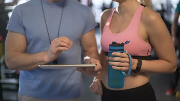 Trainer Communicating With Female Client, Creating Her Personal Workout Plan