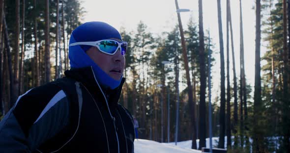 Man Looking at Sunset Sky While Skiing in Winter Forest