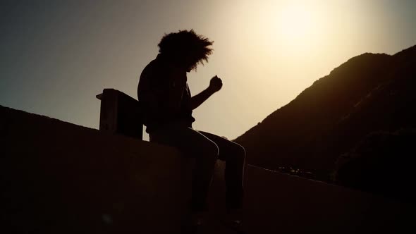 Afro man having fun dancing and listening music with vintage boombox stereo at sunset time