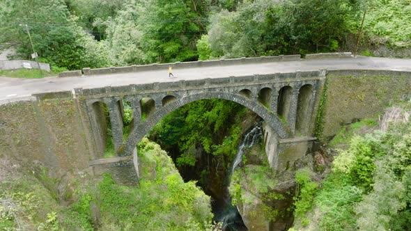 Person crossing ancient arch bridge, A Ponte Velha, Madeira; aerial