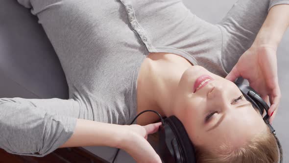 Young beautiful girl lies on a sofa in headphones