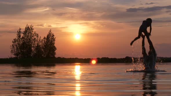 Playful Father Throws Daughter in the water, magical colorful sunset