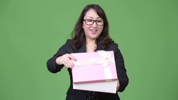 Mature Beautiful Asian Businesswoman Looking Surprised While Opening Gift Box