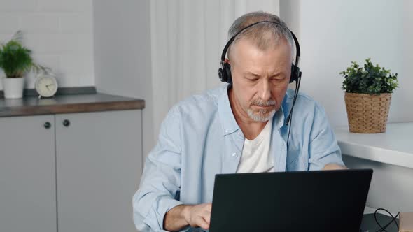 A Focused Man Headphones is Studying Online Courses Using Computer Applications