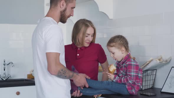 Young Father and Mother Playing with Cheerful Cute Girl in Kitchen. Portrait of Caucasian Man and