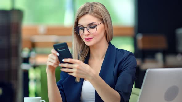 Stylish Business Female Typing Message Looking at Screen of Smartphone Having Positive Emotion