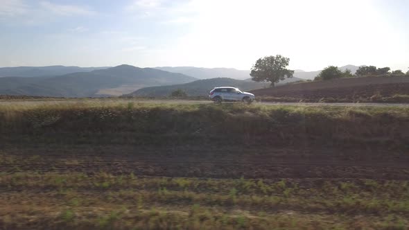 Drone view of a car driving in the countryside